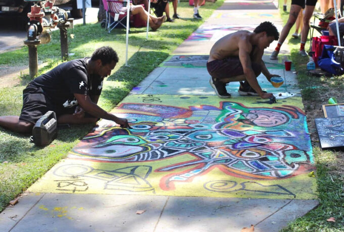 an image of two men making a chalk mural on the sidewalk together